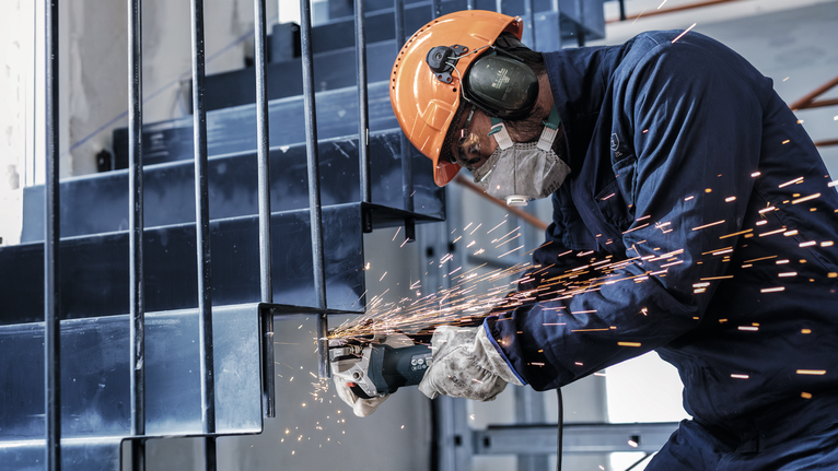 Người mặc đồ bảo hộ mài cầu thang kim loại, tạo ra tia lửa bắn ra ngoài.