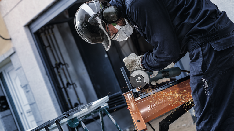 Một người mặc đồ bảo hộ sẽ mài kim loại, tạo ra tia lửa.