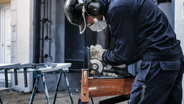 Một người mặc đồ bảo hộ sẽ mài kim loại, tạo ra tia lửa.