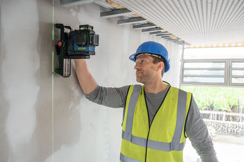 Một người mặc thiết bị an toàn đang căn chỉnh máy cân bằng laser trên tường.