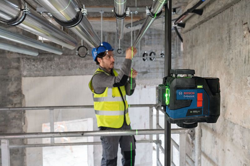 Một người mặc thiết bị an toàn đang căn chỉnh các đường ống bằng dụng cụ cân bằng laser.