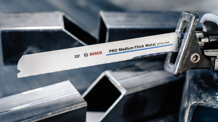 Lưỡi PRO Medium-Thick Metal precise S937BEF, 1,1 x 25 x 150 mm, 5 chiếc Lưỡi cưa qua lại được kẹp trong máy cưa, đặt gần các thanh kim loại.