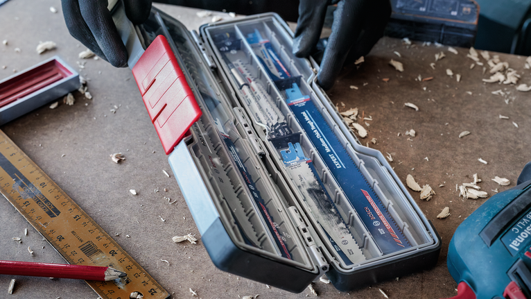 Hộp PRO Tough Box Large đựng phụ kiện, 50 x 120 x 355 mm Người mặc đồ bảo hộ đang mở hộp lưỡi cưa trên bàn làm việc.