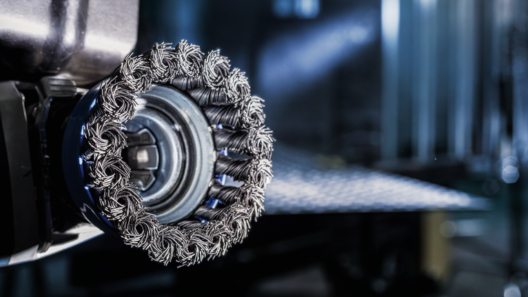 Bàn chải tròn PRO Metal clean, 75 x 0,30 mm, X-Lock Cận cảnh đầu chổi kim loại gắn trên dụng cụ điện trong môi trường công nghiệp.