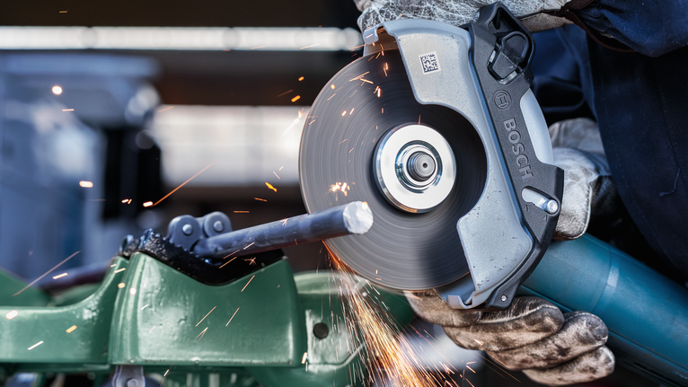 Đá cắt PRO Metal, 125 x 3 x 22,23 mm Một người mặc đồ bảo hộ đang cắt một thanh kim loại bằng máy mài góc quay.