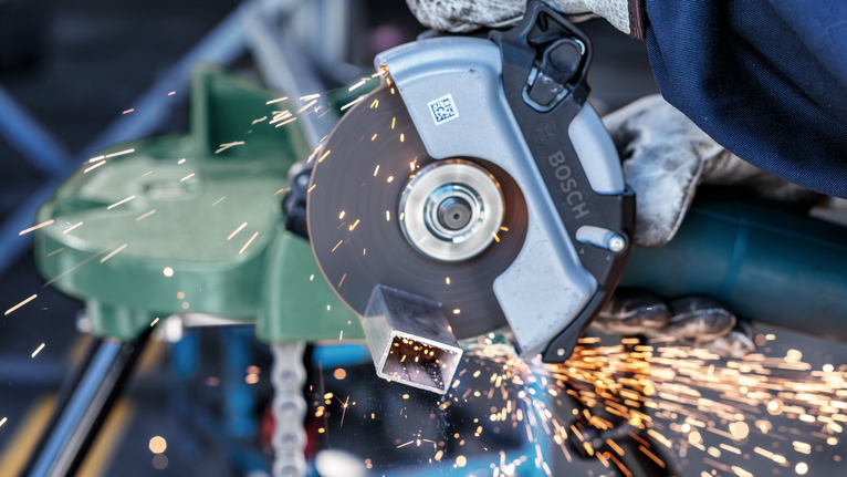 Đá cắt PRO Metal, 125 x 3 x 22,23 mm Một người mặc đồ bảo hộ đang cắt một ống kim loại bằng máy mài góc, tia lửa bắn ra.