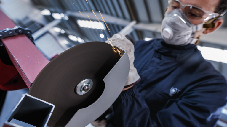 Đá cắt PRO Metal, 180 x 3 x 22,23 mm Người đeo thiết bị an toàn đang cắt kim loại bằng máy mài góc quay.