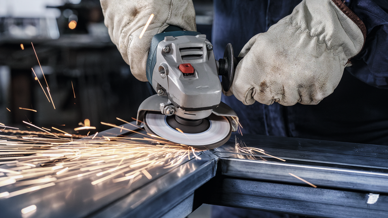 Người đeo thiết bị an toàn mài kim loại, tạo ra tia lửa sáng.