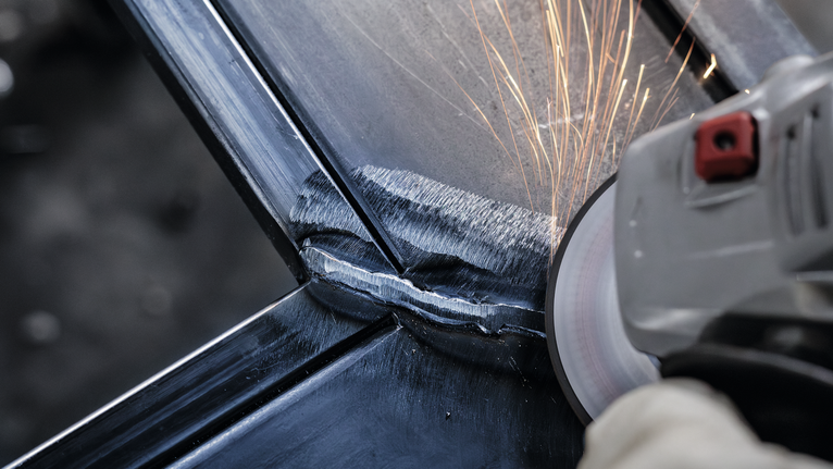 Người đeo thiết bị an toàn mài mối hàn kim loại, tạo ra tia lửa.