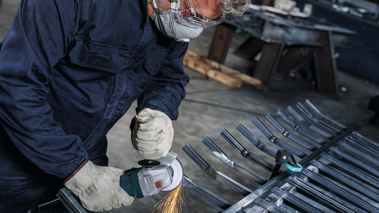 Người đeo thiết bị an toàn nghiền các thanh kim loại, tạo ra tia lửa bắn ra.