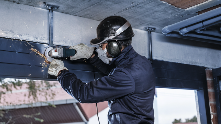 Người đeo thiết bị an toàn mài các thanh kim loại, tạo ra tia lửa.