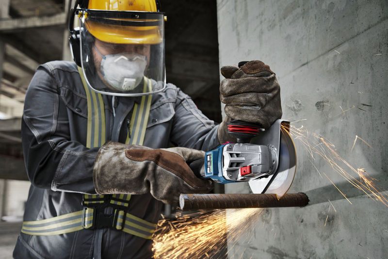 GWS 18V-15 S Một người đeo thiết bị an toàn sử dụng máy mài góc không dây để cắt thanh thép.