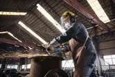 Một người đeo thiết bị an toàn sử dụng máy mài góc không dây để cắt kim loại, tạo ra tia lửa.