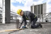 Một người mặc đồ bảo hộ đang cắt thép cây bằng máy cắt điện tại công trường xây dựng.
