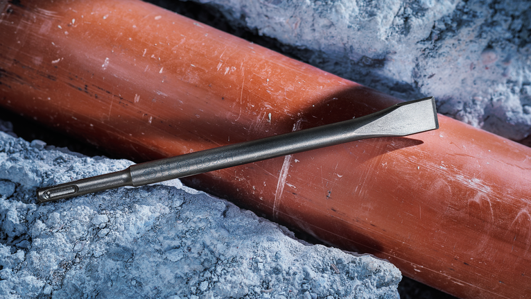 Một chiếc đục nằm trên một đường ống được bao quanh bởi bê tông vỡ.