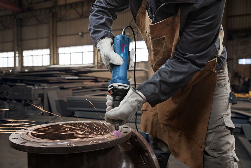 GGS 30 LPS Một người mặc đồ bảo hộ sẽ mài kim loại bằng máy mài thẳng, tạo ra tia lửa điện.