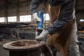 Một người mặc đồ bảo hộ sẽ sử dụng máy mài thẳng để mài kim loại, tạo ra tia lửa.