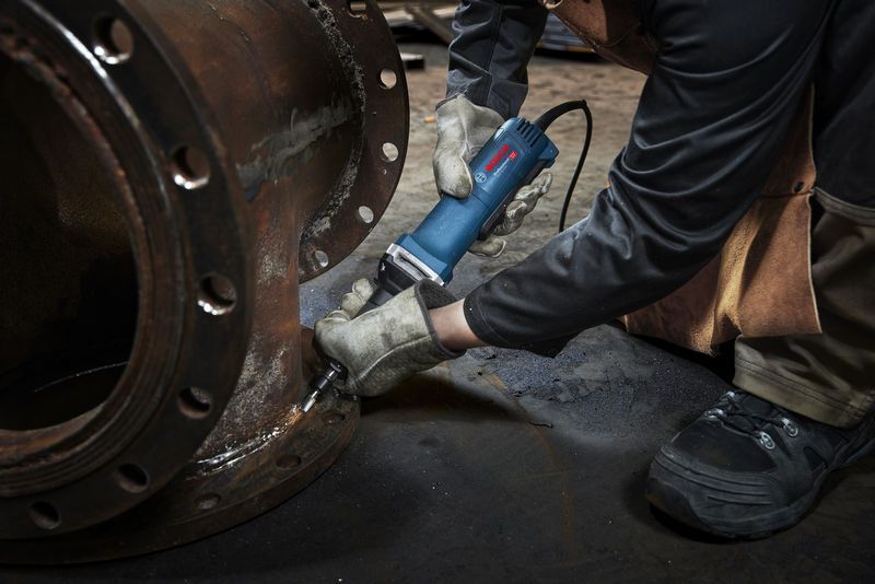 GGS 30 LPS Một người mặc thiết bị an toàn sử dụng máy mài thẳng trên mặt bích kim loại.