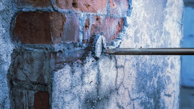 Một cái đục khoan vào gạch và bê tông, phá vỡ bề mặt tường.