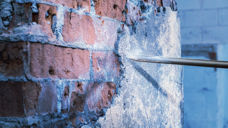 Đục để loại bỏ lớp vữa bê tông khỏi tường gạch.