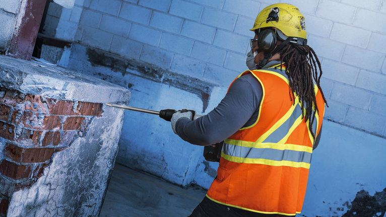 Người mặc đồ bảo hộ sử dụng dụng cụ phá dỡ để phá bê tông và gạch.