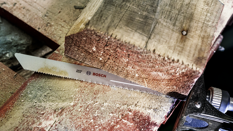 Lưỡi cưa cắt qua một thanh gỗ dày trong xưởng.