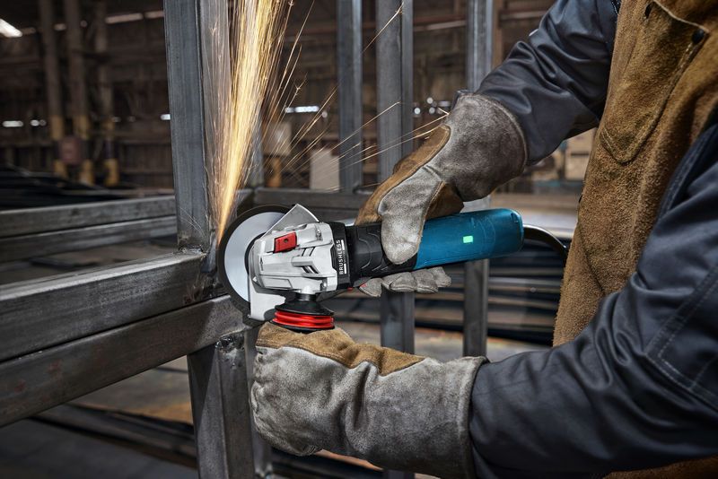 Một người mặc đồ bảo hộ đang mài kim loại, tạo ra tia lửa trong môi trường công nghiệp.