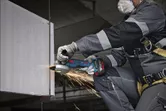 Một người mặc thiết bị an toàn mài một thanh kim loại, tạo ra tia lửa.