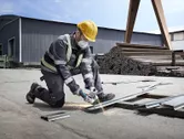 Một người mặc đồ bảo hộ sử dụng máy mài góc để cắt kim loại ngoài trời.