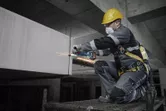 Một người mặc đồ bảo hộ đang mài kim loại tại công trường xây dựng.