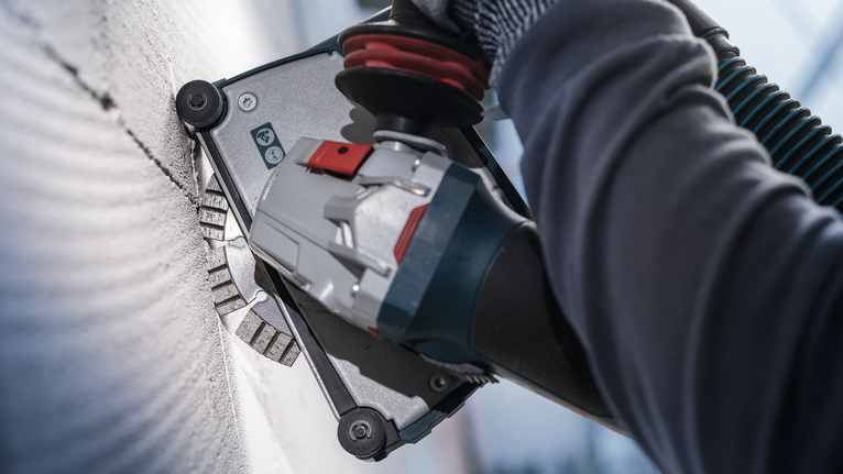 Người đeo thiết bị an toàn mài tường bằng dụng cụ điện.