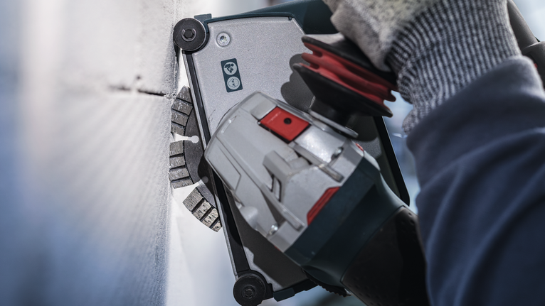 Người đeo thiết bị an toàn sử dụng dụng cụ điện để cắt tường.