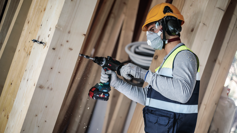 Bộ mũi khoan xoắn ốc PRO Wood, L235, 6 chiếc Một người mặc đồ bảo hộ đang khoan vào một thanh gỗ.