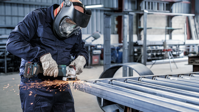Một người mặc đồ bảo hộ sẽ mài kim loại, tạo ra tia lửa.