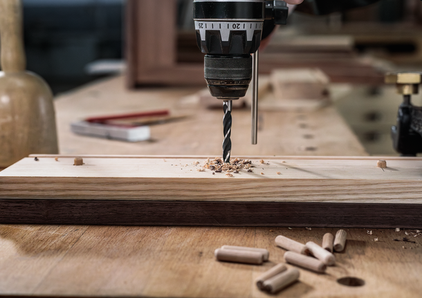 Bộ mũi khoan đầu đinh nhỏ PRO Wood, 7 chiếc Một người sử dụng máy khoan điện để khoan một lỗ trên tấm gỗ trên bàn làm việc.