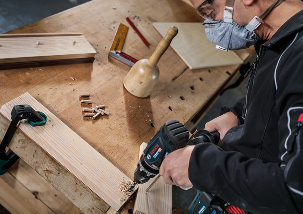 Bộ mũi khoan đầu đinh nhỏ PRO Wood, 7 chiếc Người đeo thiết bị an toàn đang khoan lỗ trên tấm ván gỗ trên bàn làm việc.