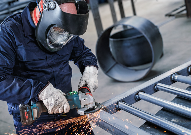 Người đeo thiết bị an toàn mài các thanh kim loại, tạo ra tia lửa.