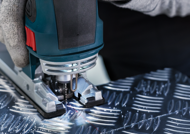 Lưỡi cưa lọng PRO Alu T127D, 100 mm, 5 chiếc Một người mặc đồ bảo hộ sử dụng máy cưa lọng để cắt kim loại có hoa văn.