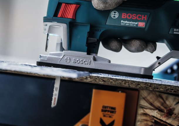 Lưỡi cưa lọng PRO Alu T127D, 100 mm, 5 chiếc Một người mặc đồ bảo hộ đang sử dụng máy cưa lọng để cắt một tấm ván gỗ.