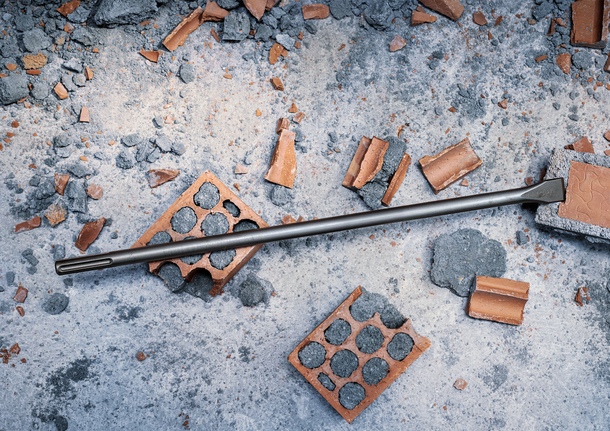 Chiếc đục được bao quanh bởi những viên gạch vỡ và mảnh vụn bê tông tại một công trường xây dựng.