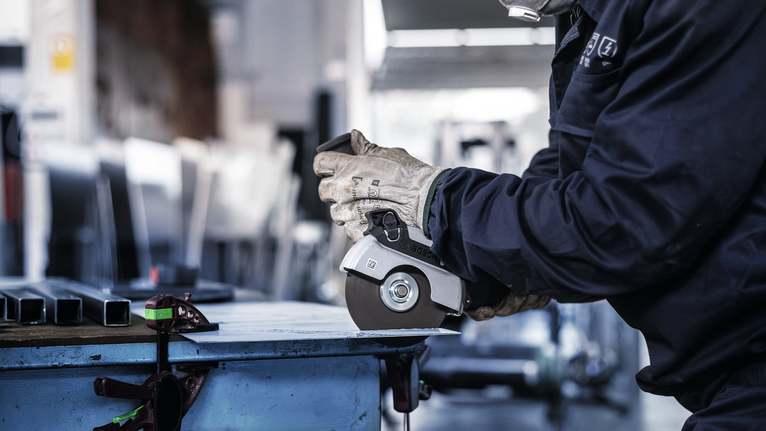 Đá cắt liên kết PRO Stainless Steel and Metal, 125 x 1 x 22,23 mm, thẳng Một người mặc đồ bảo hộ sử dụng máy mài góc để cắt kim loại.