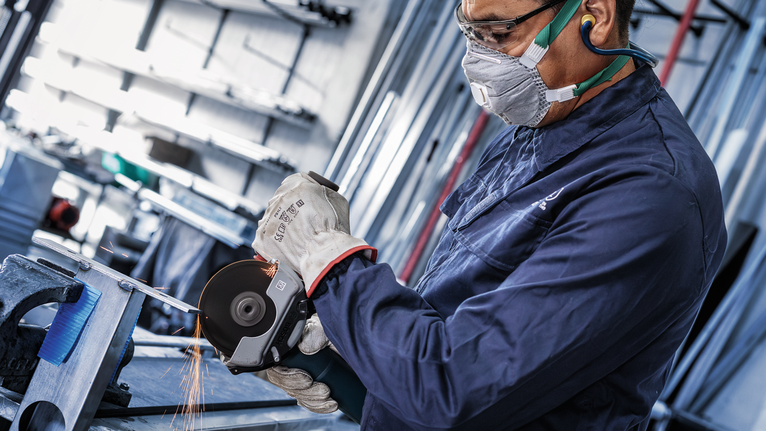 Đá cắt liên kết PRO Stainless Steel and Metal, 125 x 1,6 x 22,23 mm, X-Lock, thẳng, oSa Một người mặc đồ bảo hộ sẽ mài kim loại, tạo ra tia lửa.