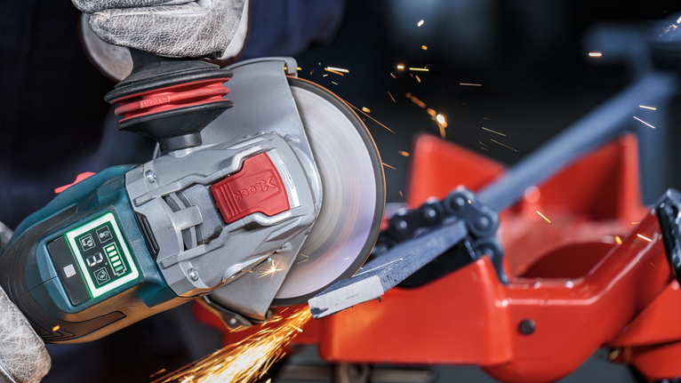 Đá cắt liên kết PRO Metal, 125 x 1,6 x 22,23 mm, X-Lock Người đeo thiết bị an toàn sử dụng máy mài góc để cắt một thanh kim loại.