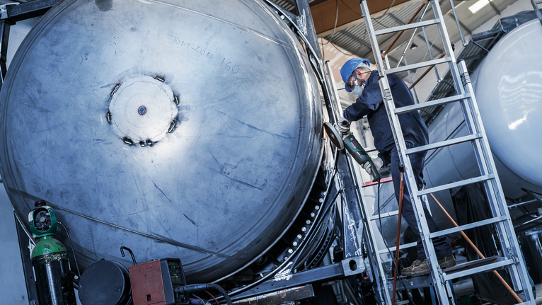 Đĩa mài PRO Stainless Steel, 180 x 6 x 22,23 mm Người đeo thiết bị an toàn mài mép của một chiếc thùng kim loại lớn trên thang.