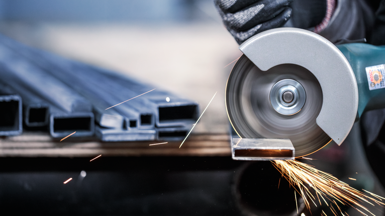 Đá cắt PRO Stainless Steel and Metal, 105 x 1 x 16 mm Một người mặc đồ bảo hộ đang cắt một ống kim loại bằng cưa tròn, tia lửa bắn ra.