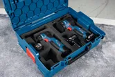 Bộ máy khoan và máy vặn vít không dây được sắp xếp trong hộp đựng màu xanh.