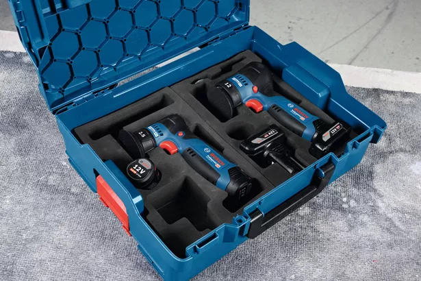 GEX 12V-77 Dụng cụ điện không dây và pin được sắp xếp trong hộp đựng màu xanh trên bề mặt làm việc.