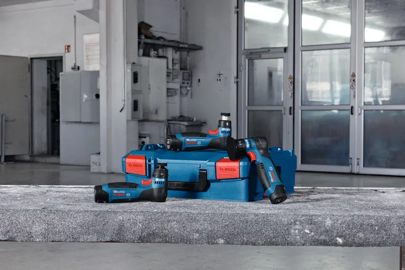Máy chà nhám quỹ đạo ngẫu nhiên không dây và một hộp màu xanh đặt trên bề mặt bê tông trong xưởng.