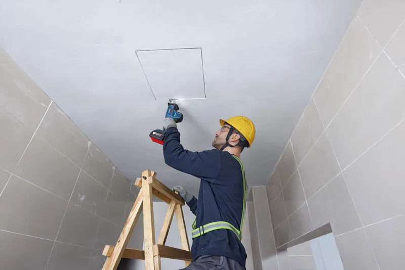 GSA 18V-24 Một người mặc đồ bảo hộ đang sử dụng máy cưa lọng để cắt tấm trần nhà.
