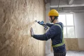 Người mặc thiết bị an toàn sử dụng máy cưa lọng để cắt vào bức tường gỗ.